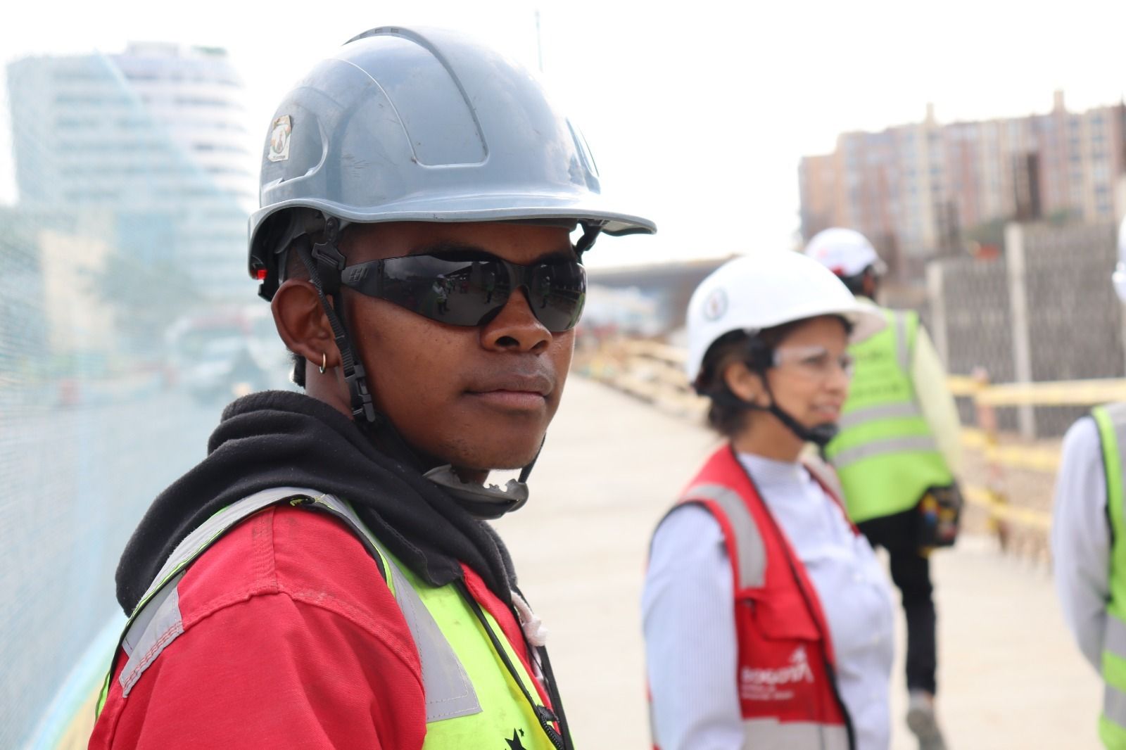 Un trabajador de obra, copn gafas oscuras y caso mira a la cámara