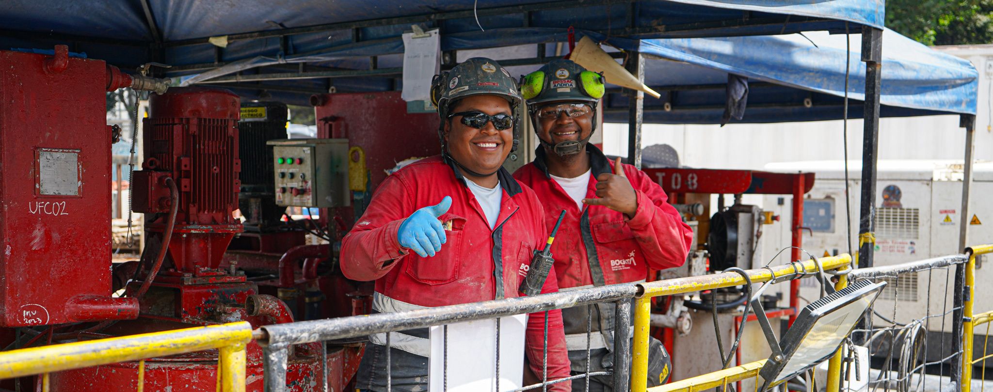 Dos trabajadores sonríen a la cámara y levantan sus dedos pulgares 