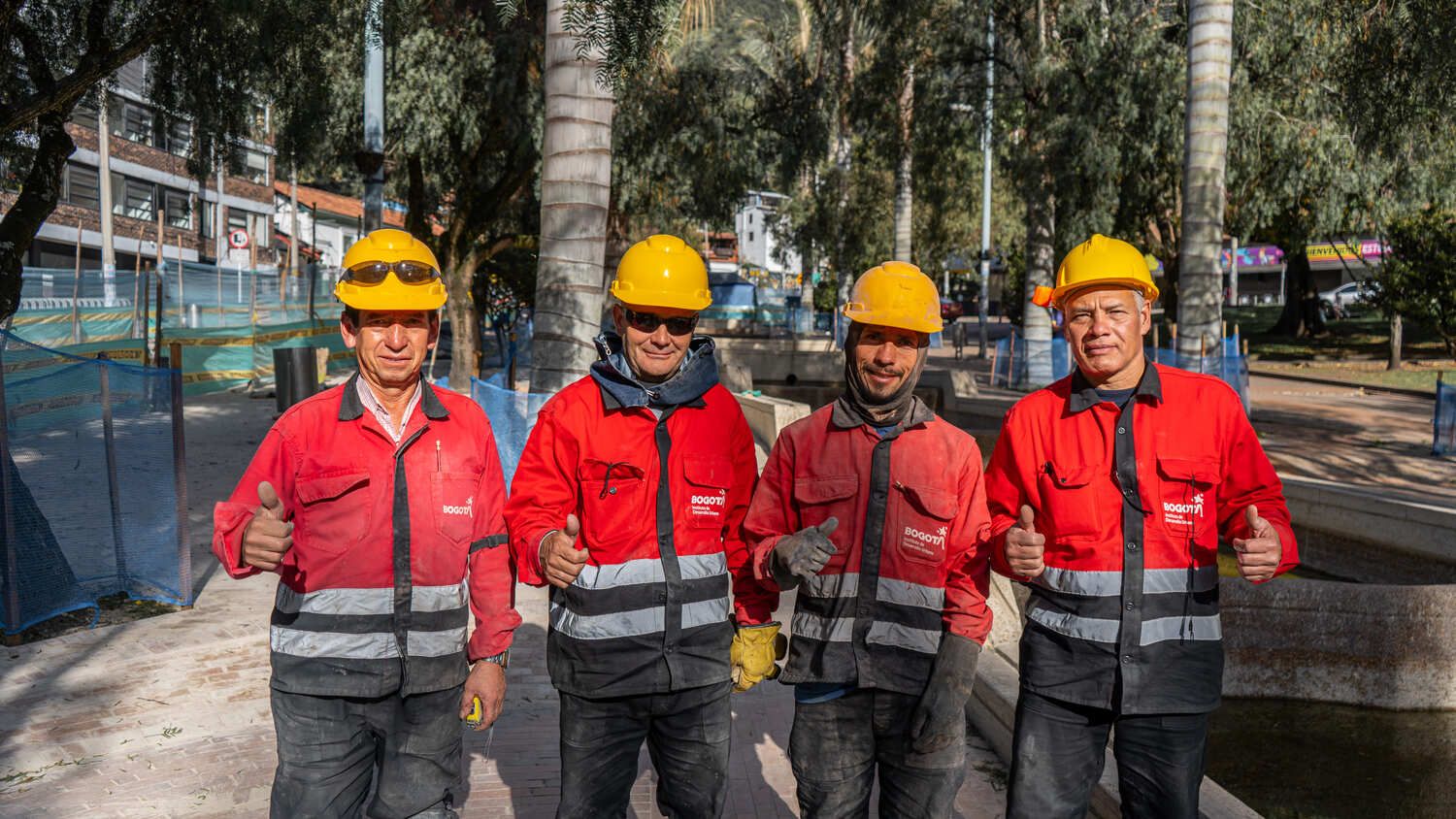 Cuatro trabajadores de obra sonríen a la cámara con su pulgar arriba