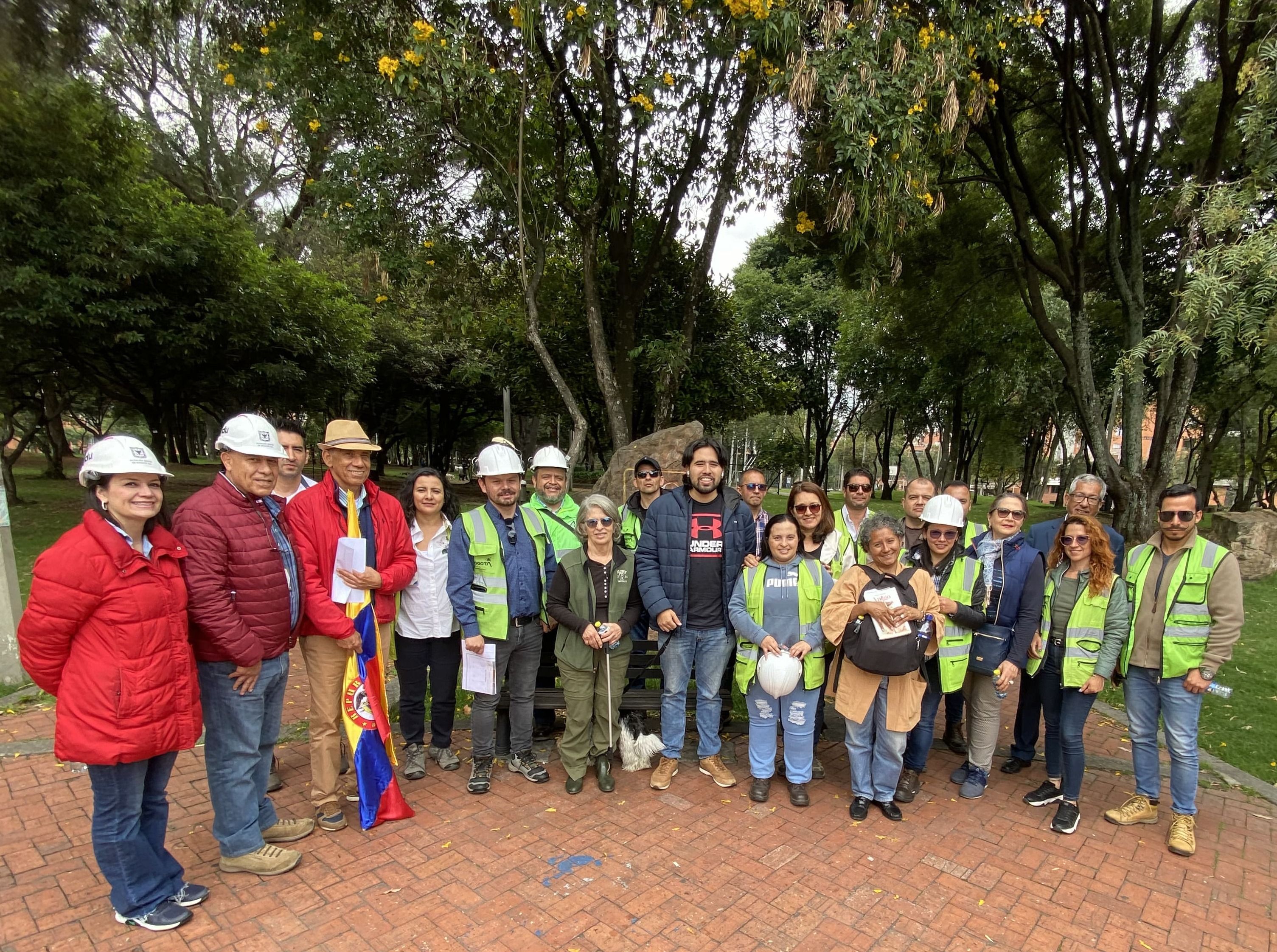 Un grupo de personas de la comunidad con representantes del IDU y del contratista posan para la foto en el acceso principal del parque Los Molinos