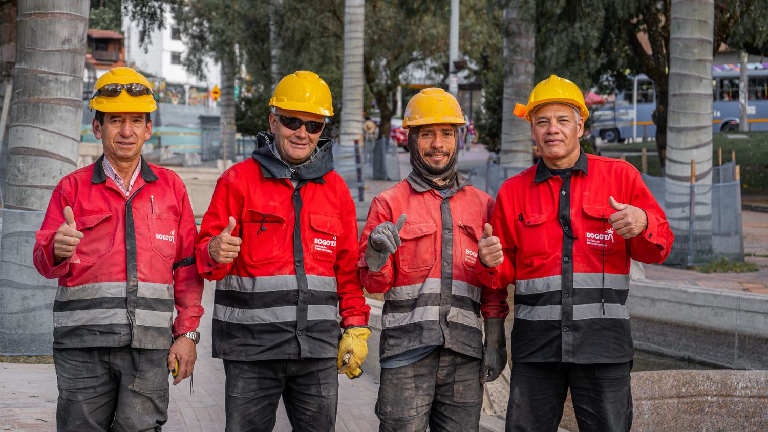 Cuatro trabajadores de obra miran a la cámara y tienen arriba el pulgar de la mano arriba para indicar que está bien