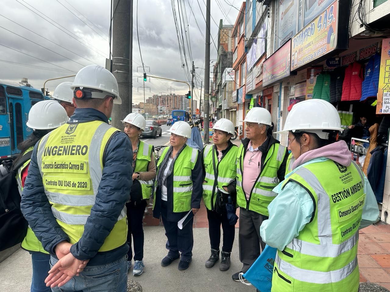Un grupo de personas, identificadas con chalecos del IDU conversan sobre una calle peatonal